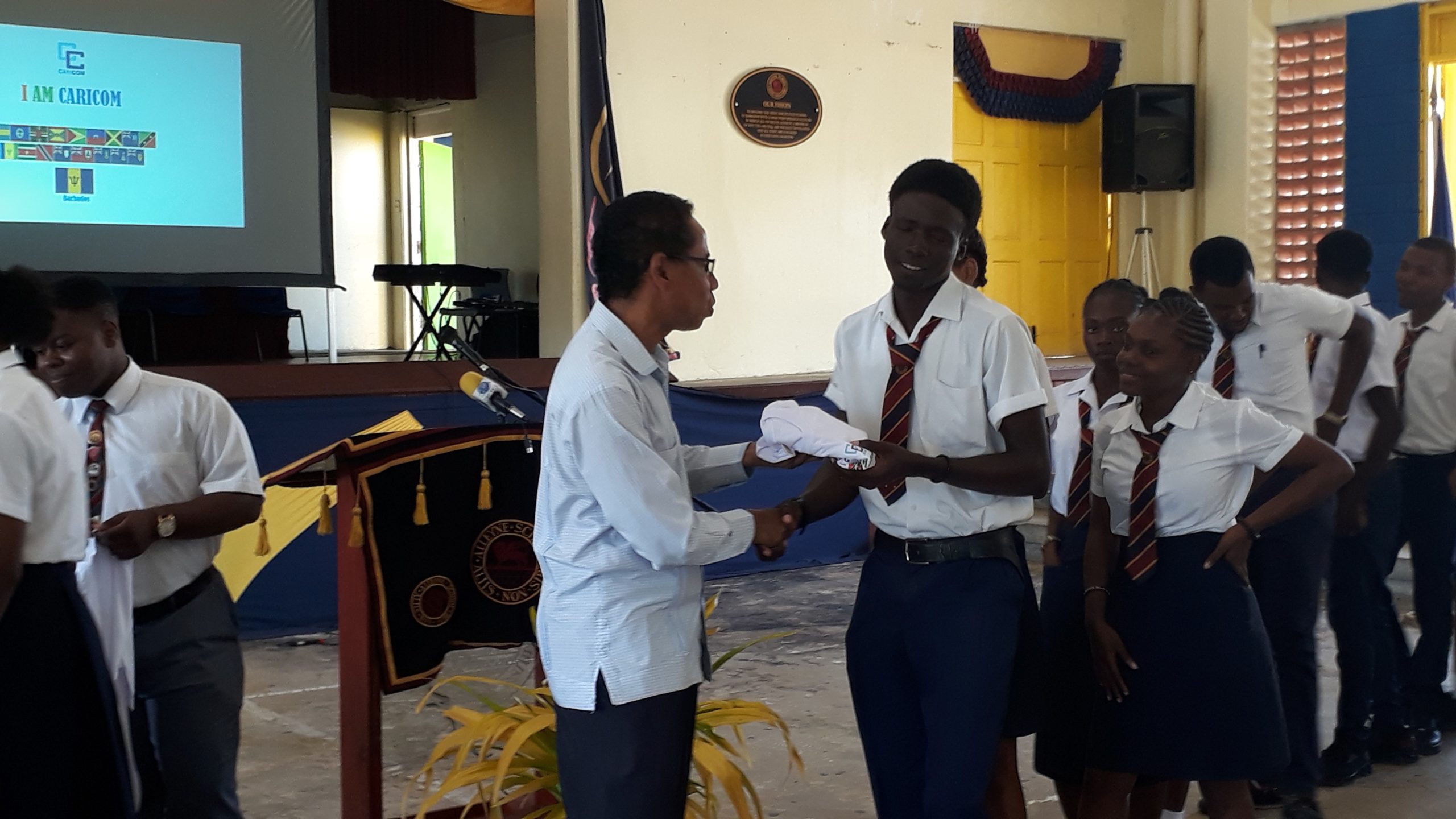 Ambassador Comissiong presenting an 'I Am CARICOM' T-shirt to a student during the launch